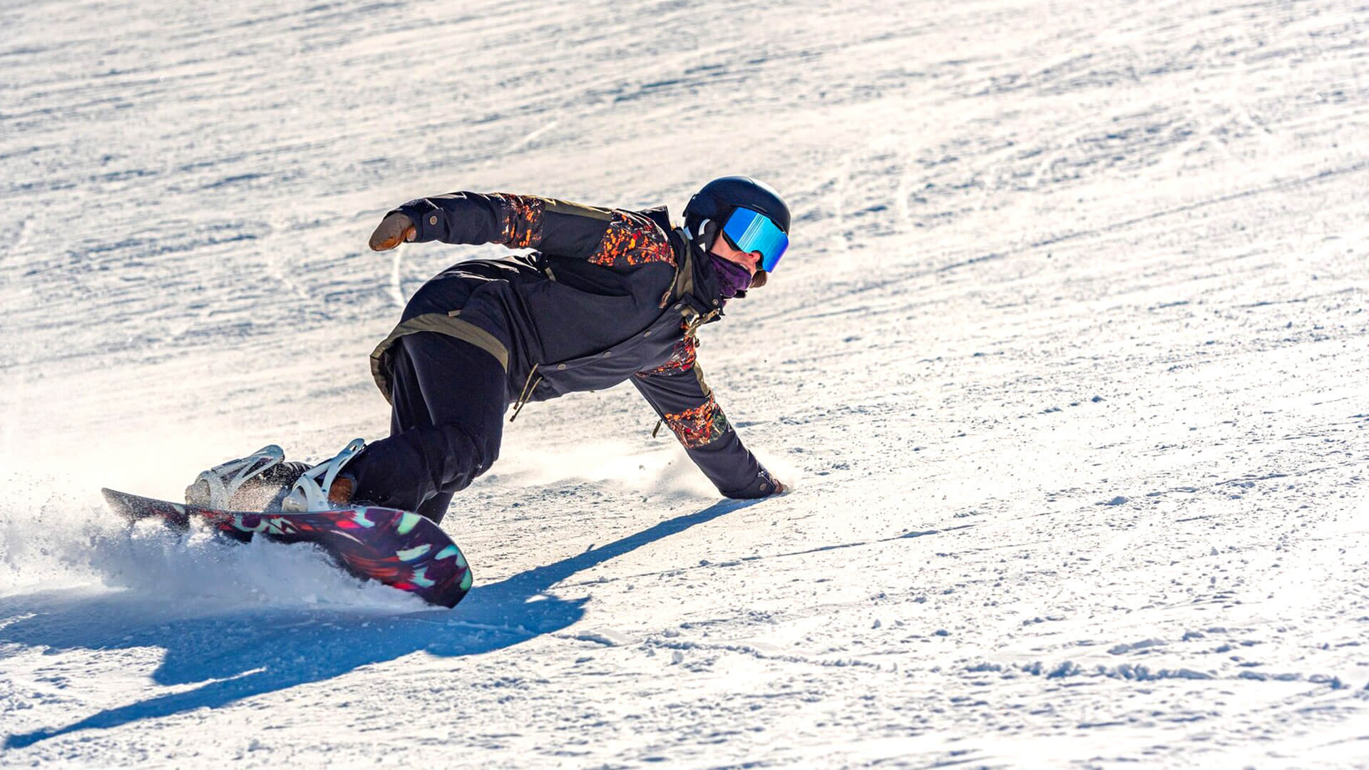 Uno snowboarder con giacca e pantaloni tecnici neri sulla neve